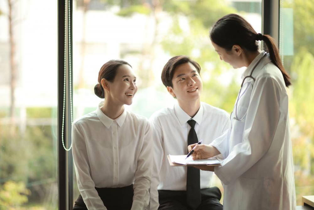 A doctor reviews medical forms with a couple